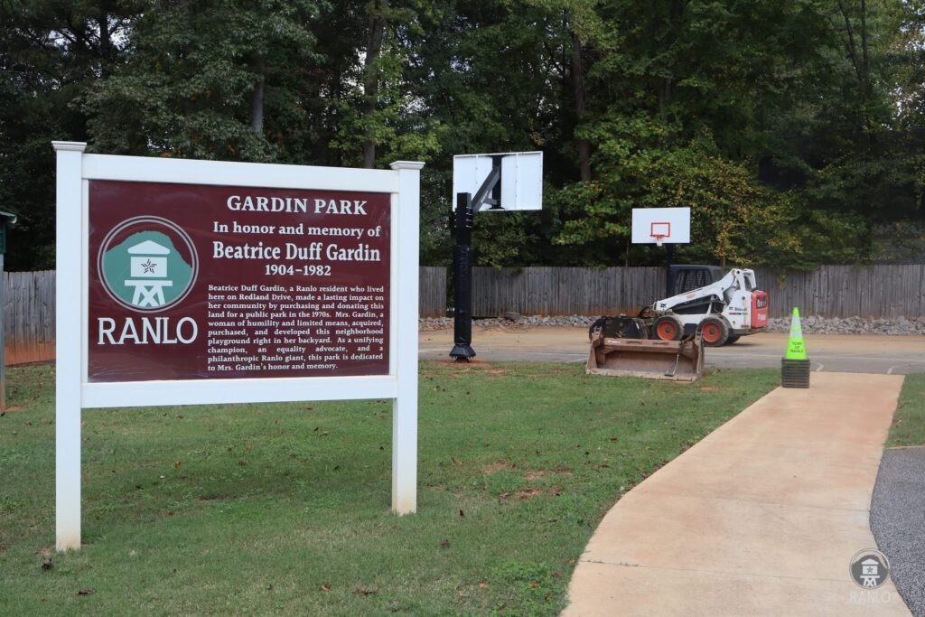 The Gardin Park sign honoring Beatrice Duff Gardin, with the basketball court and new hoops in the background.